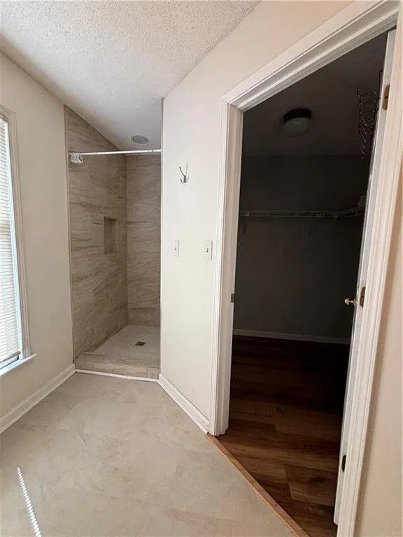 Bathroom featuring hardwood / wood-style flooring, a textured ceiling, and a tile shower