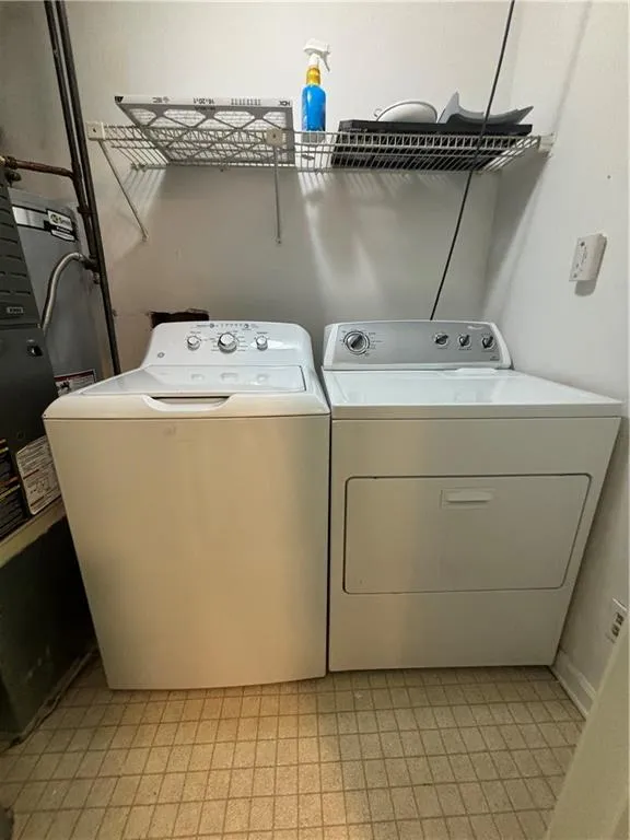 Clothes washing area featuring light tile patterned floors and washing machine and dryer