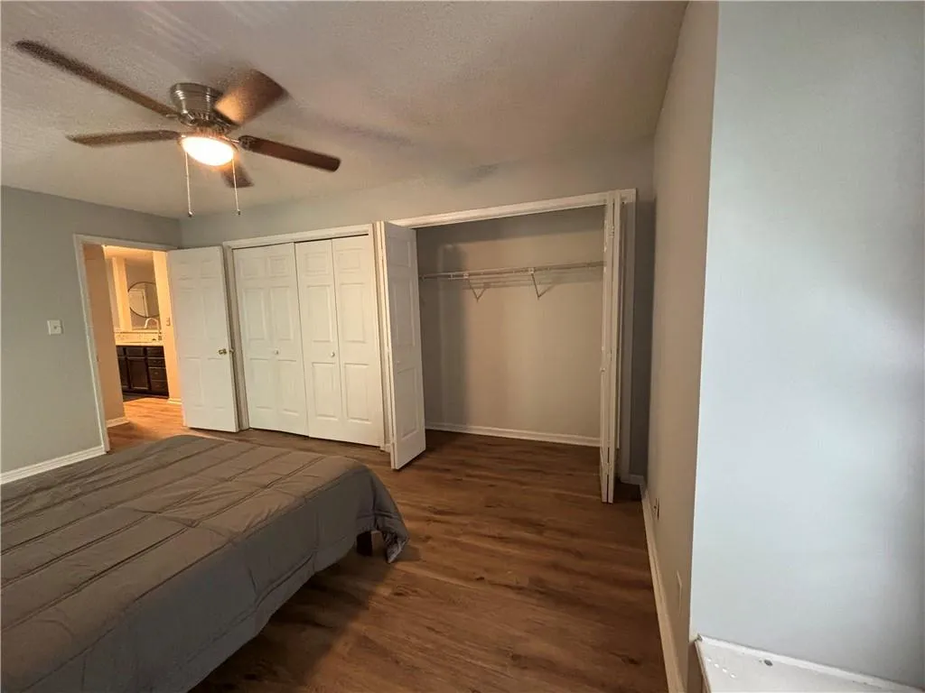 Bedroom with dark hardwood / wood-style flooring, two closets, and ceiling fan