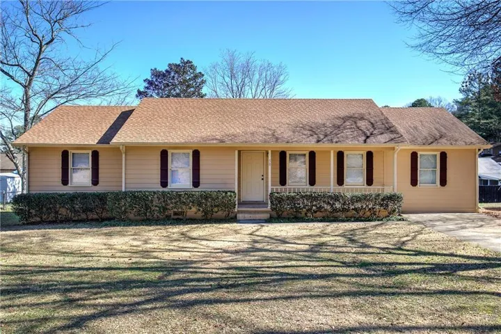 Ranch-style residence featuring horizontal siding, a gabled roofline, and symmetrical front windows with dark shutters