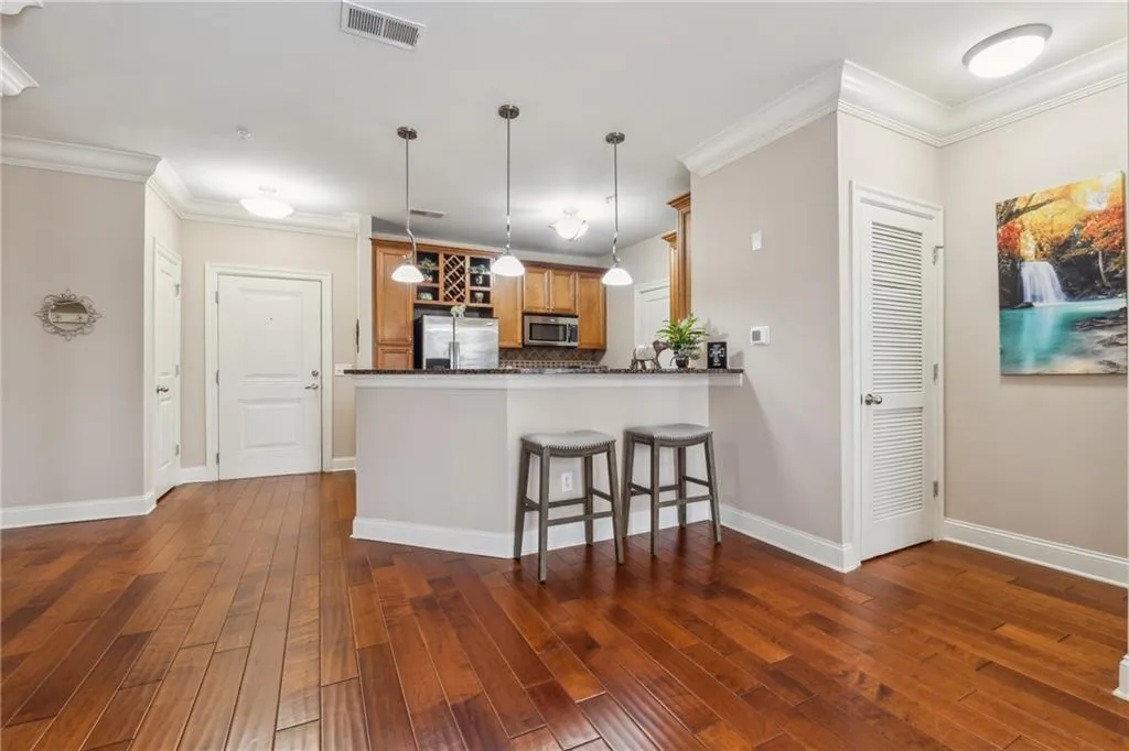 Kitchen featuring dark hardwood / wood-style floors, kitchen peninsula, stainless steel appliances, a breakfast bar area, and tasteful backsplash