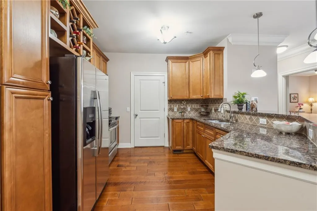 Kitchen with sink, tasteful backsplash, decorative light fixtures, dark hardwood / wood-style flooring, and stainless steel appliances