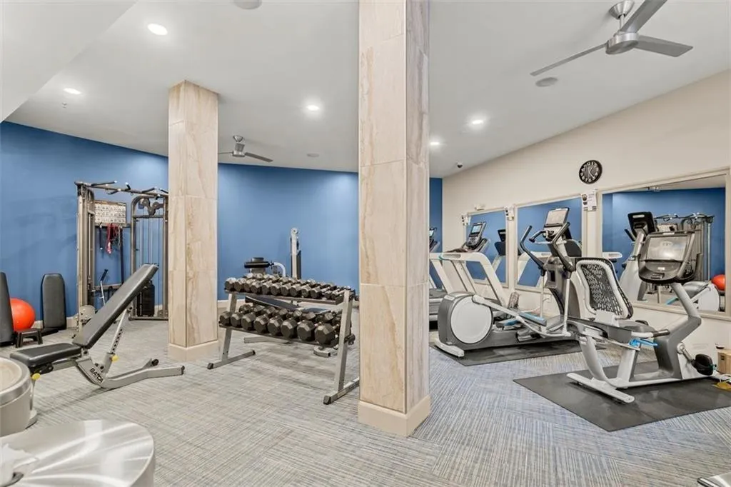 Exercise room with ceiling fan and light carpet