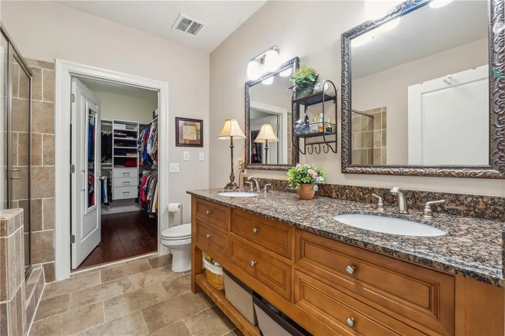 Bathroom with a shower with door, double vanity, toilet, and tile floors