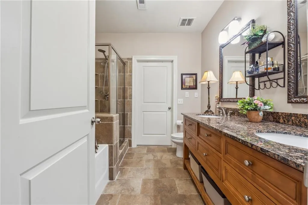 Bathroom featuring toilet, tile flooring, dual vanity, and a bath