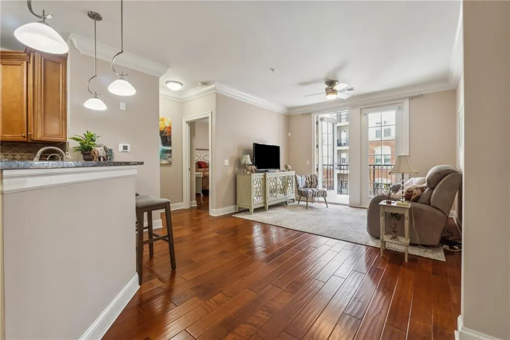 Living room featuring ceiling fan, crown molding, and dark wood-type flooring