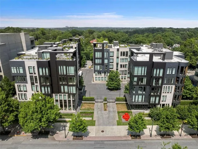 Contemporary multi-story architecture with a dark and light facade, extensive window placement, rooftop terraces with plantings, and a central courtyard entrance