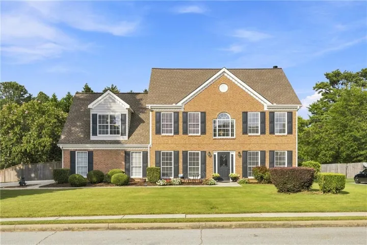 Brick exterior with a gabled roof and dormer windows, featuring black louvered shutters
