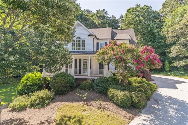 White two-story home featuring a covered front porch with white railings and columns