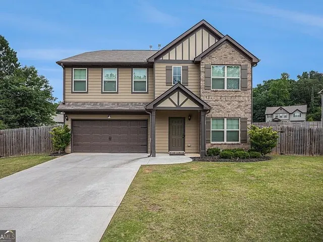 Two-story exterior with a brick and siding facade, featuring a covered entry, an attached two-car garage, and a concrete driveway