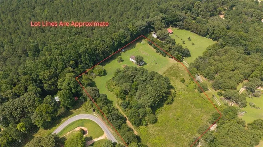 Expansive acreage featuring a curved paved road, mature trees, and open grassy areas
