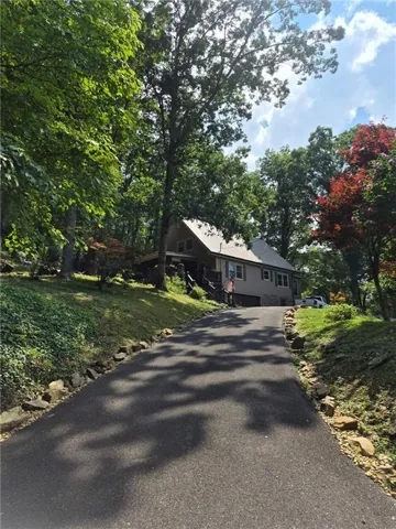 Asphalt driveway leading to a residence with a light-colored siding facade