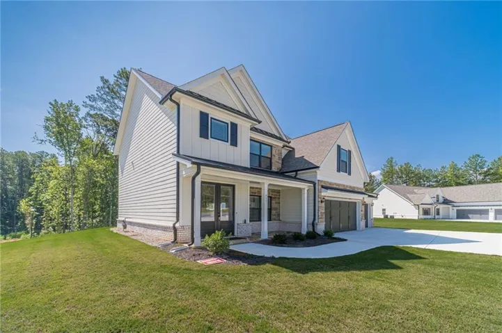 Modern farmhouse exterior with white siding, black-framed windows, and stone accents