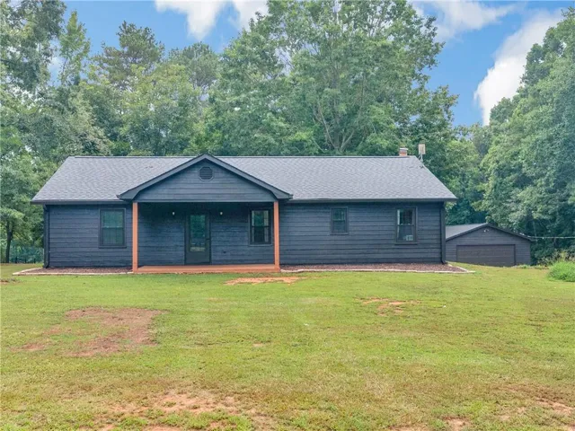 Dark-toned exterior siding with a covered porch, wood posts, and a dark asphalt shingle roof