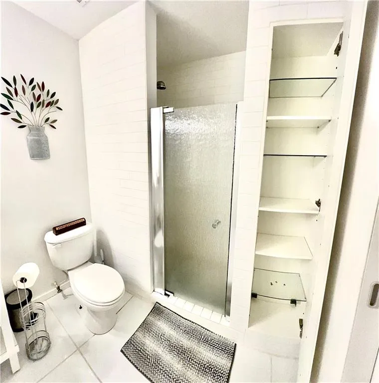 Bathroom with walk in shower, toilet, and tile floors