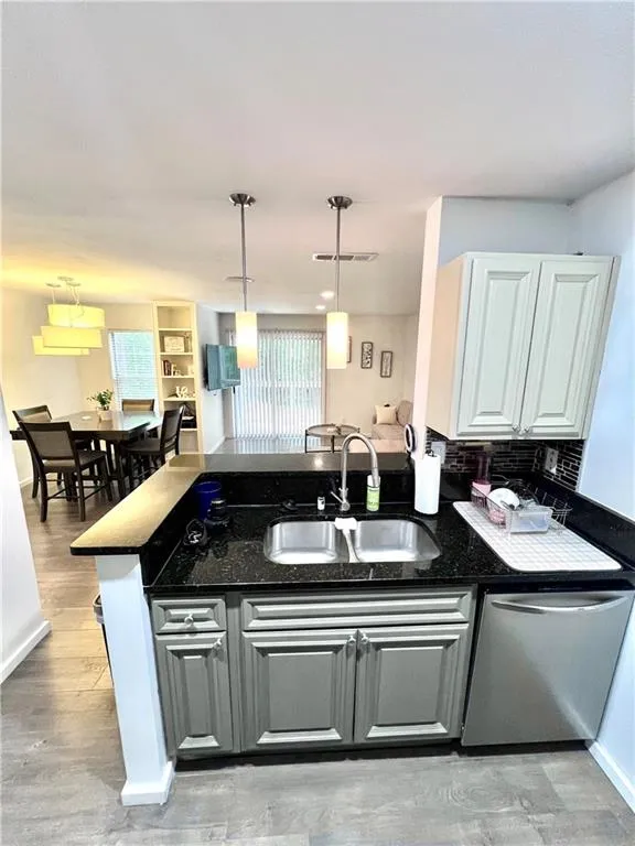 Kitchen featuring pendant lighting, kitchen peninsula, sink, and stainless steel dishwasher