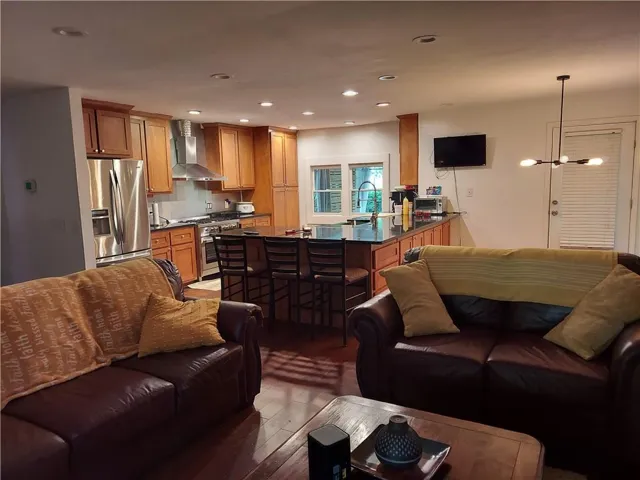 Open-concept living area featuring wood-finish flooring, a kitchen with stainless steel appliances, a center island with seating and recessed lighting. Great gathering spot for family and friends.