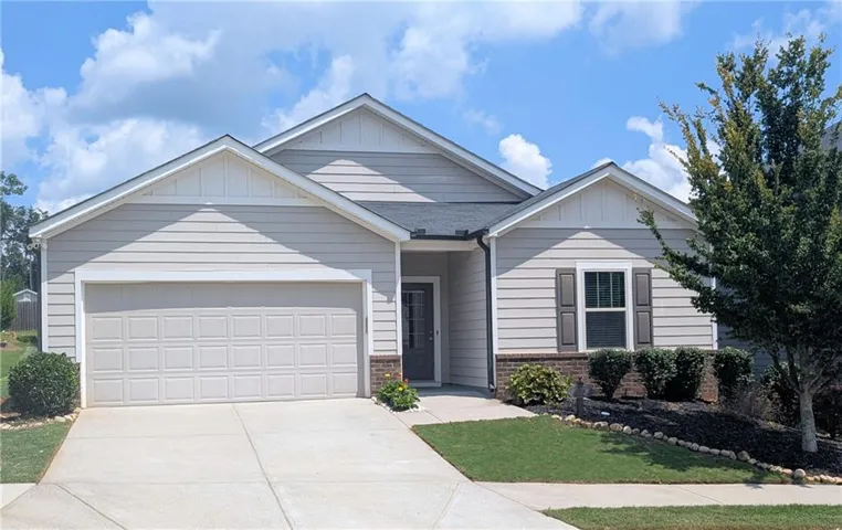 Charming single-story residence featuring white fiber cement siding, a two-car garage with white paneled doors, and a pitched roofline with architectural detail