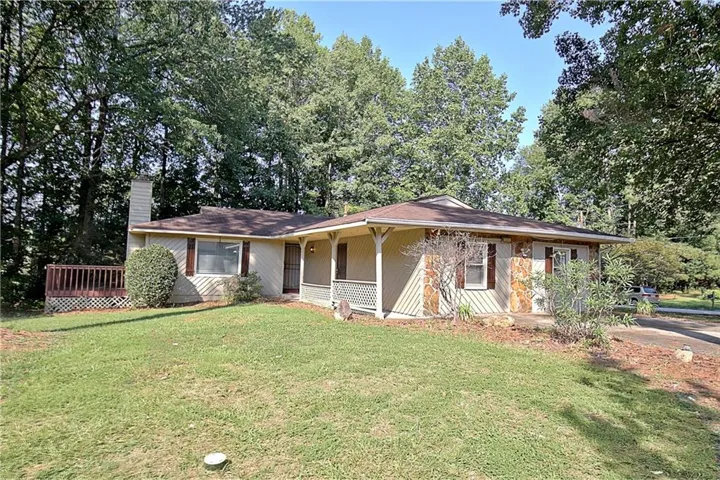 Single-story residence featuring a covered front porch, stone and siding exterior, and a side deck