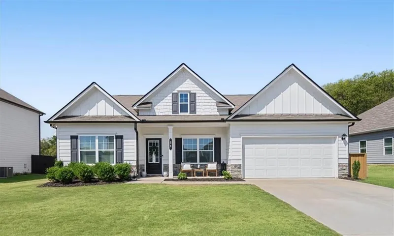 Single-story residence featuring a two-car garage, white siding, dark shutters, and a covered front entry