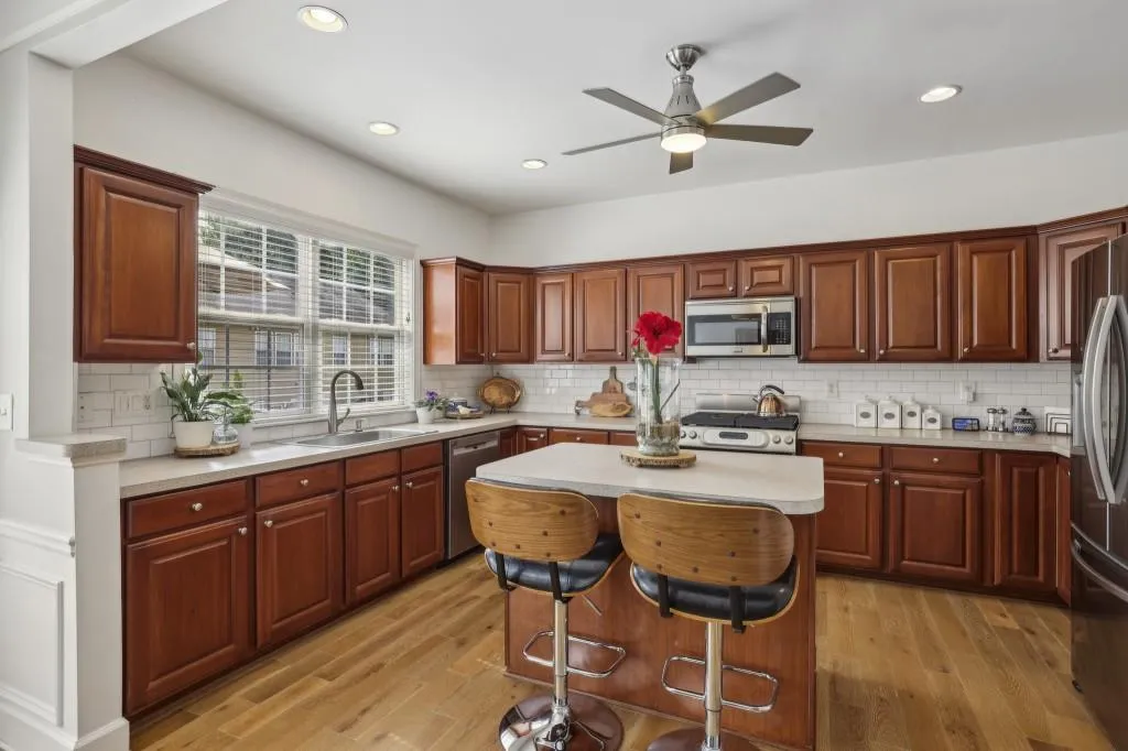 Kitchen With Dark Cabinetry, Tile Backsplash, &  An Island With A Breakfast Bar