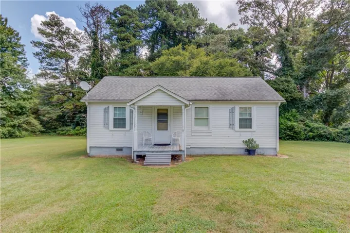 White siding exterior with a covered porch and mature trees