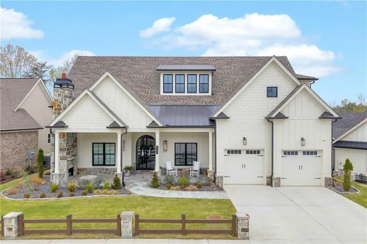 Modern farmhouse style home featuring a porch, a shingled roof, board and batten siding, concrete driveway, and a standing seam roof