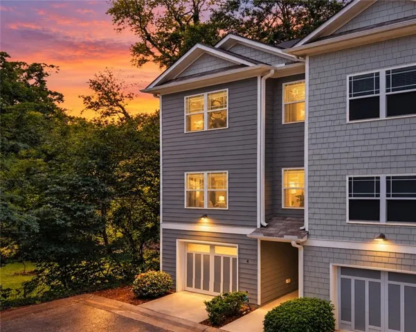 Contemporary townhome with multi-toned siding, attached garage, and exterior lighting fixtures