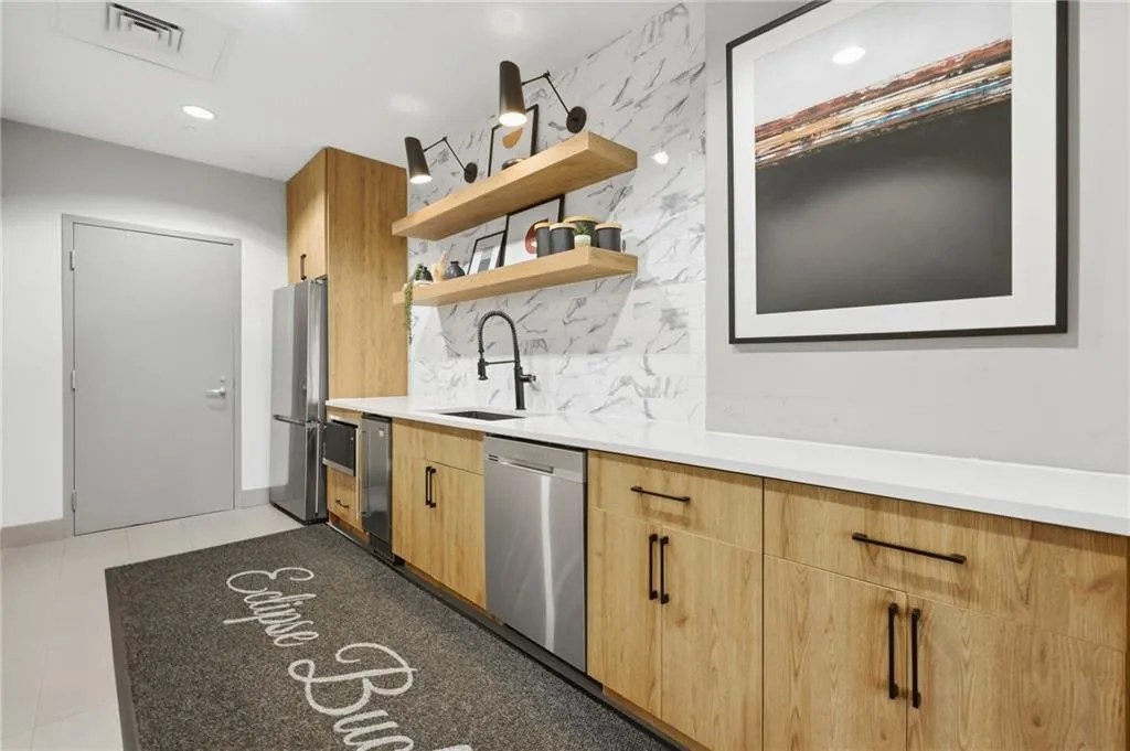 Wood-finish cabinetry, stainless steel appliances, a white countertop, and a marble-patterned backsplash