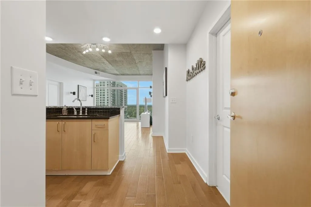 Open concept living space with wood-finish flooring, exposed concrete ceiling, and a kitchen island featuring a dark countertop