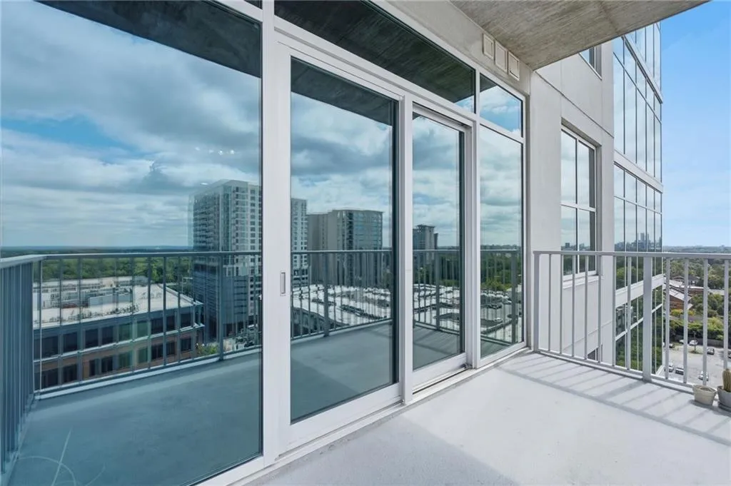 Expansive balcony with concrete flooring, aluminum railing, and a sliding glass door system