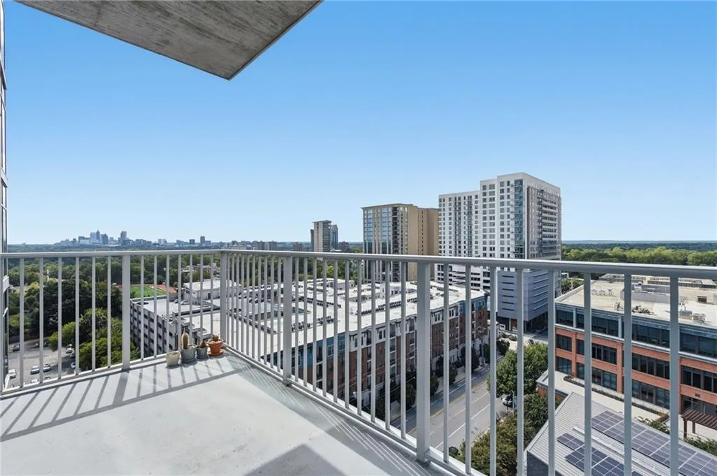 Outdoor balcony with a solid surface floor and metal railings, featuring urban and distant skyline scenery