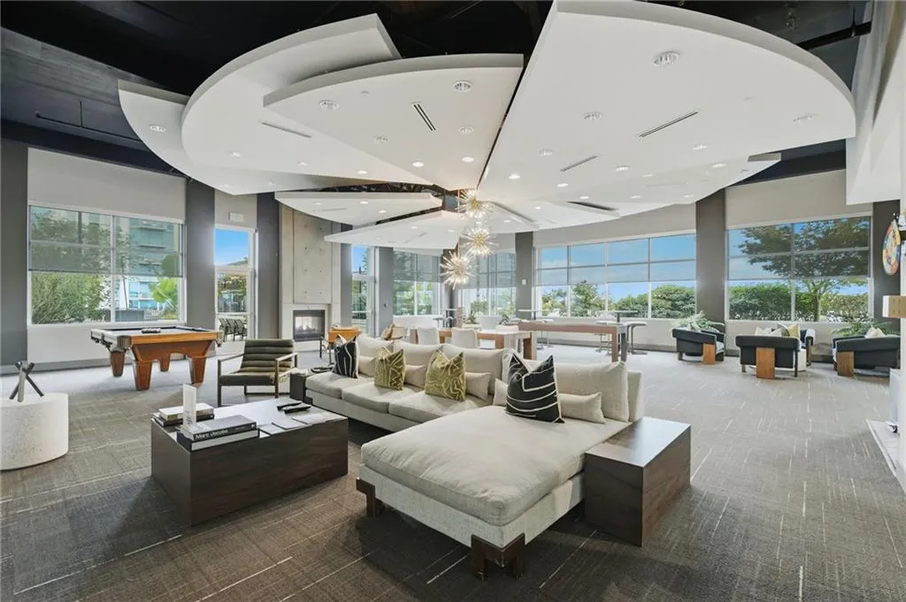Expansive common area featuring a unique multi-level ceiling design, large windows, a fireplace, and patterned carpet flooring