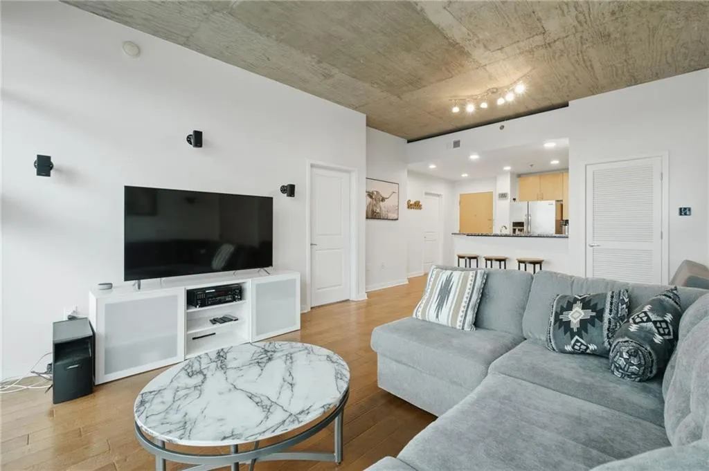 Hardwood flooring throughout the living area, complemented by a textured concrete ceiling and recessed lighting