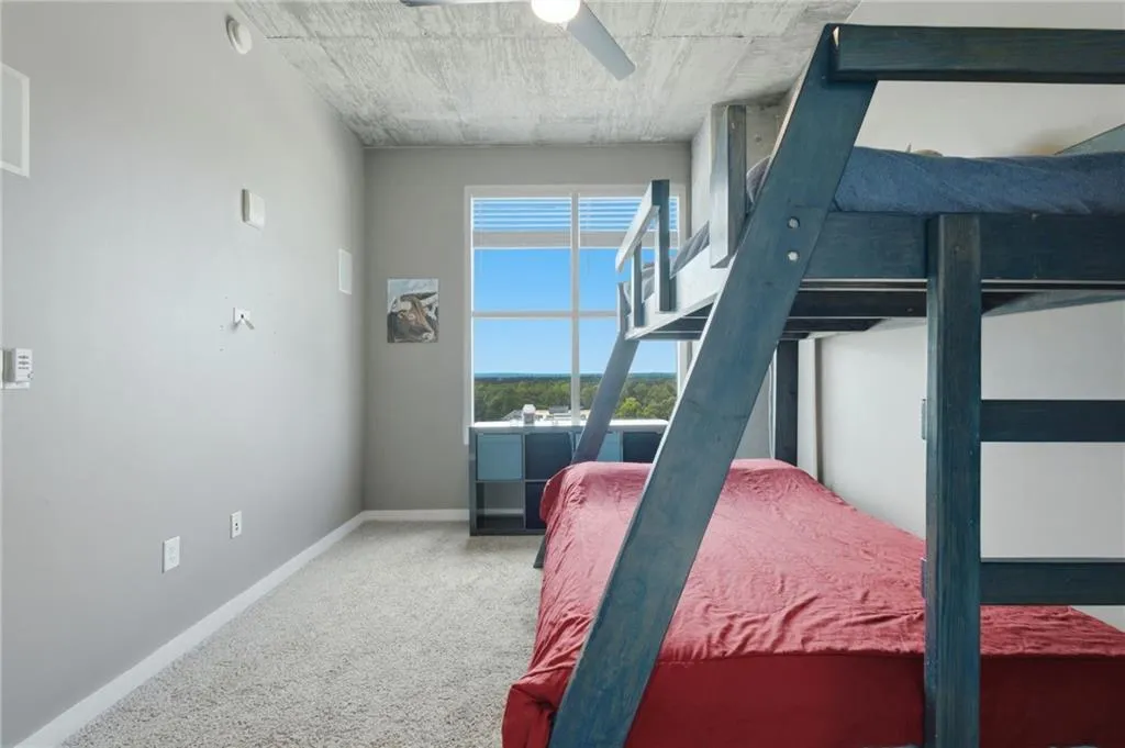 Carpeted flooring with painted walls, a window featuring blinds, and an exposed concrete ceiling