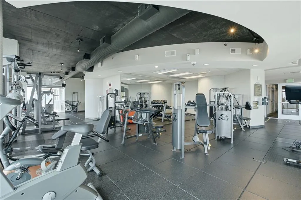 Fitness center with rubberized flooring, exposed ductwork, recessed lighting, and a variety of exercise equipment