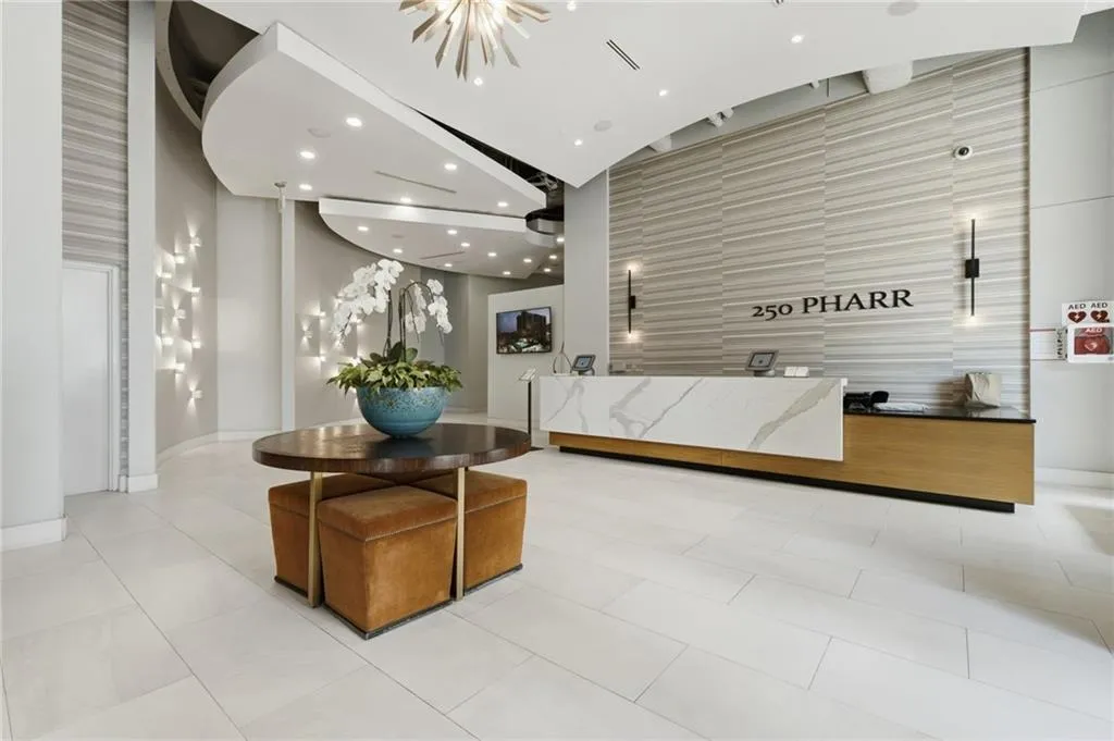 White tile flooring, reception desk with a white stone-finish countertop, textured wall paneling, curved architectural ceiling, and recessed lighting