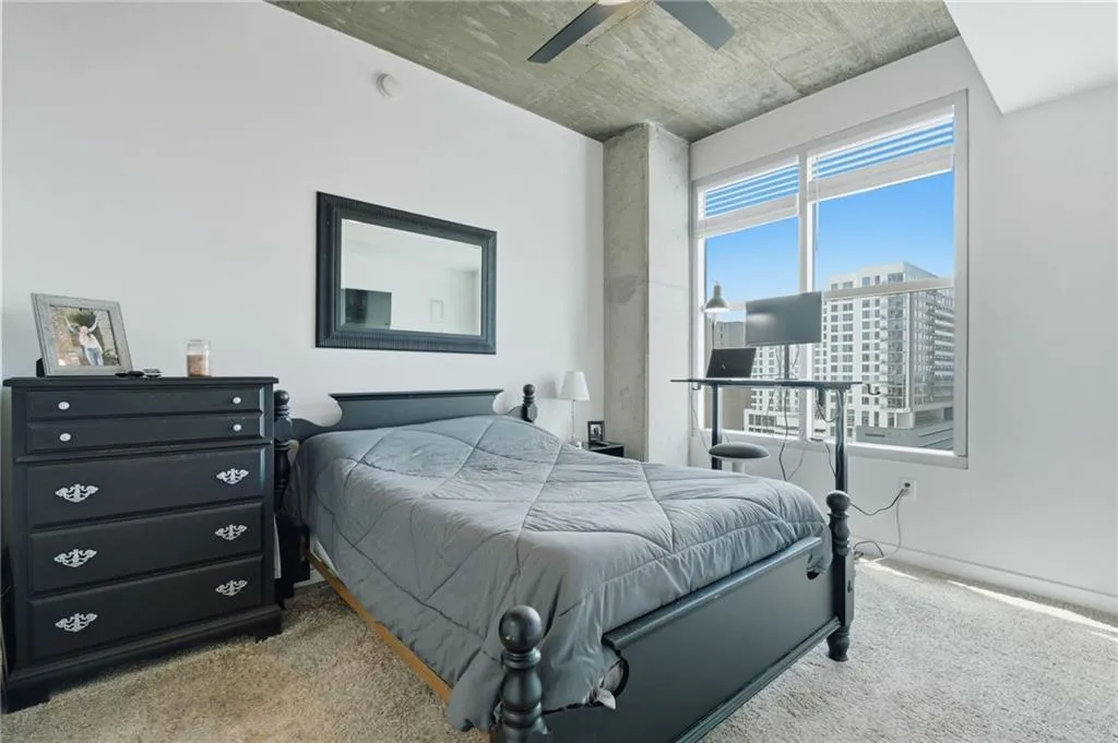 Expansive window with roller shades, concrete ceiling, concrete structural column, light-toned carpeting
