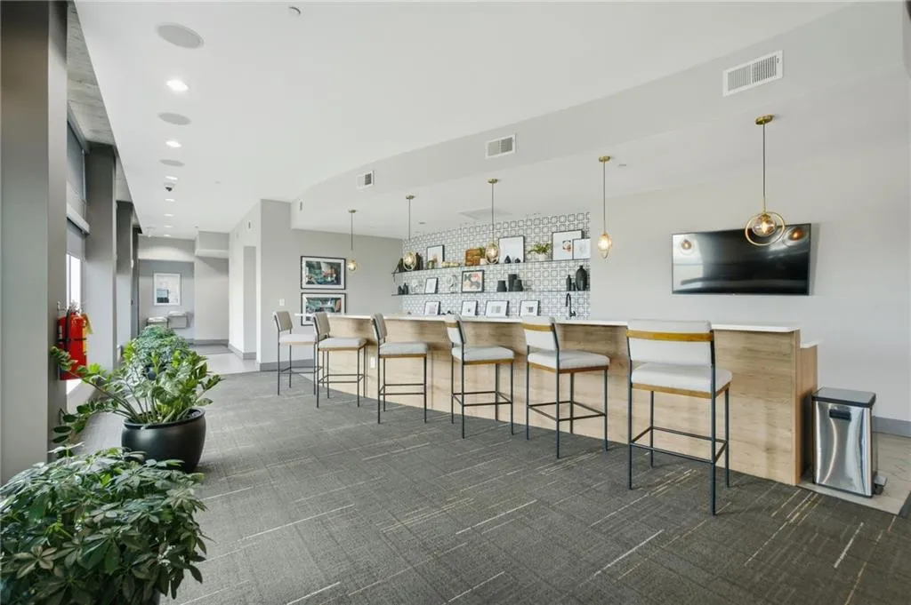 Open concept common area featuring a built-in bar, recessed lighting, and patterned carpet flooring