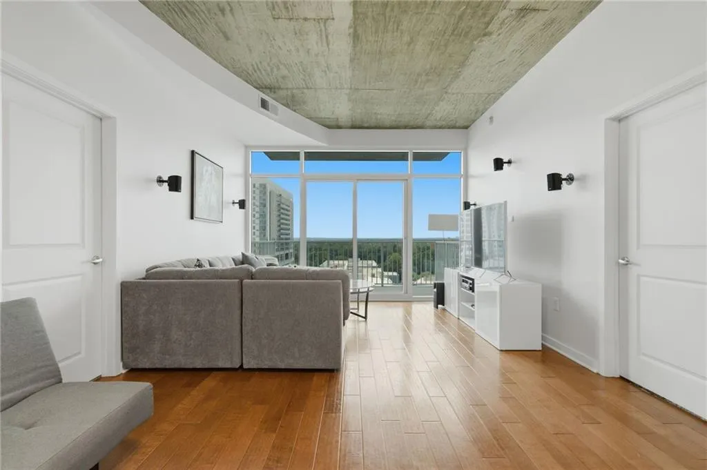 Wood-finish flooring, full-height glass windows, and an exposed concrete ceiling