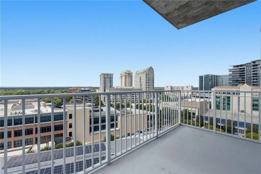 Concrete balcony with metal railing, featuring a cityscape backdrop