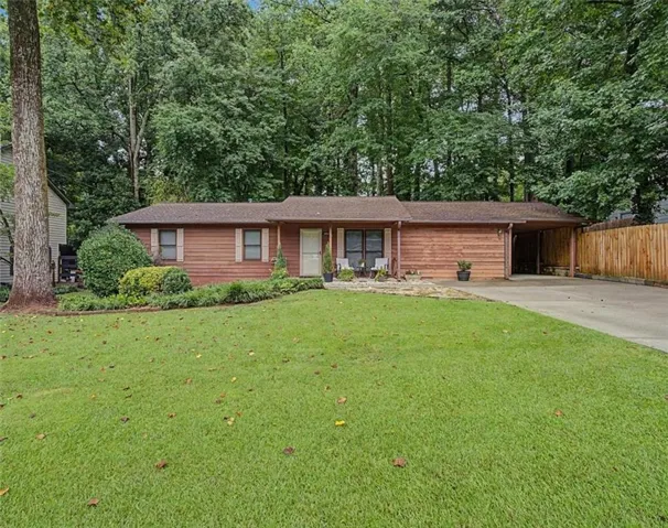 Wood-sided single-story residence with a covered carport, established front lawn, and mature landscaping