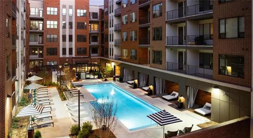Courtyard with a rectangular pool, multiple lounge chairs, and striped umbrellas