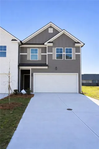 View of front of house with a garage, board and batten siding, concrete driveway, and a front yard