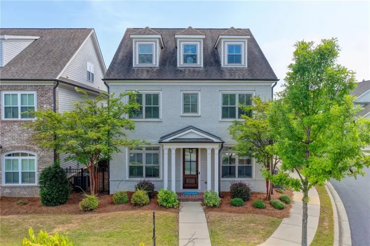 Traditional-style residence featuring a dormer roofline, brick exterior, and a covered portico entrance