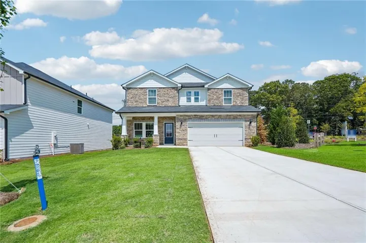Two-story residence featuring a stone and siding exterior, an attached two-car garage, and a covered front porch