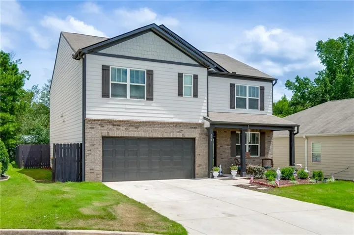 Two-story residence featuring light siding, brick veneer accents, a dark roof, and dark trim