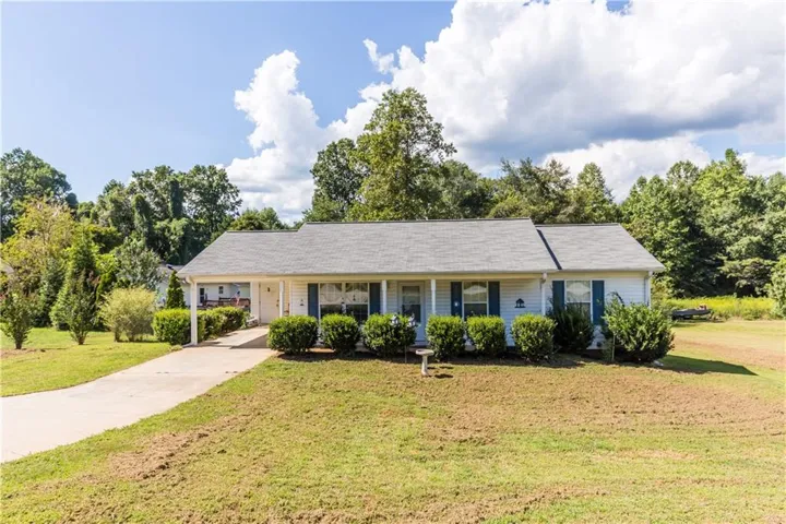Ranch-style exterior with a covered porch, white siding, blue window shutters, and a concrete driveway