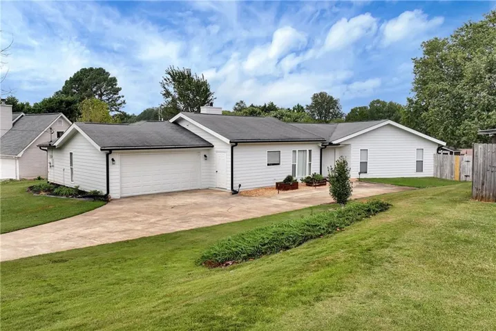 New white vinyl siding, a contrasting dark shingle roof, attached garage, concrete driveway, and established lawn create a fresh and inviting exterior.