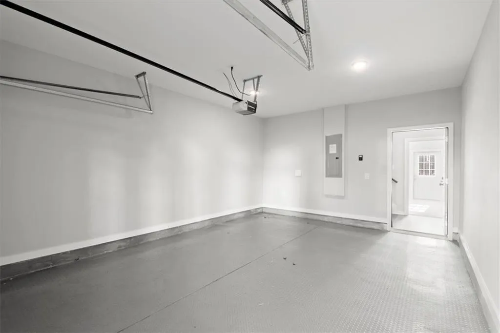 Garage with baseboards and electric panel
